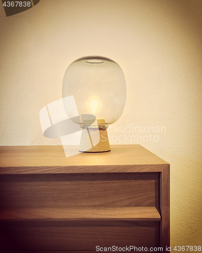 Image of Retro style glass lamp on a wooden dresser