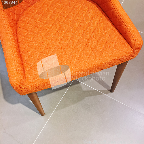 Image of Bright orange armchair on tile floor