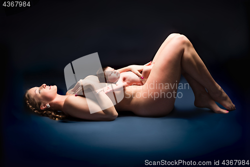 Image of Happy woman lying on her back with baby on her stomach