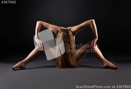 Image of Naked woman is sitting on a black background.