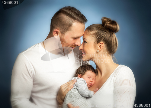 Image of Portrait of young happy couple embracing to their newborn.