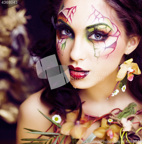 Image of beauty woman with face art and jewelry from flowers orchids clos