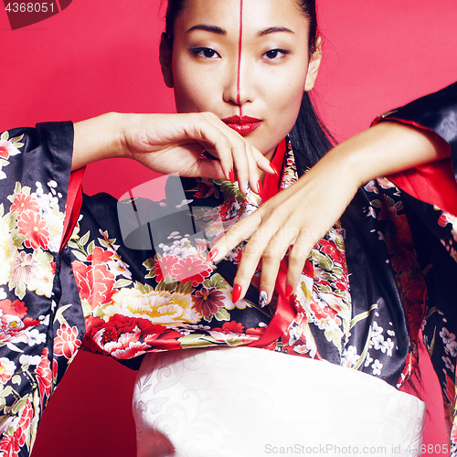 Image of young pretty geisha on red background posing in kimono, oriental people concept 