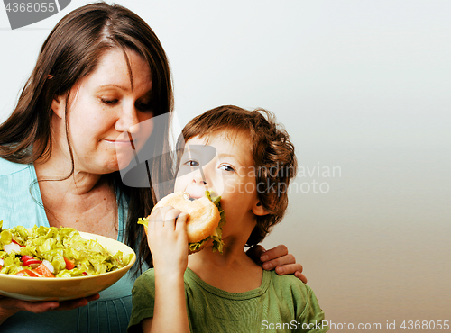 Image of mature woman holding salad and little cute boy with hamburger te