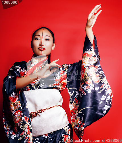 Image of young pretty geisha on red background posing in kimono, oriental people concept 