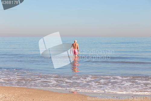 Image of Senior man back stands in the sea in winter.