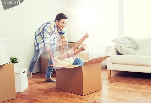 Image of happy couple having fun with boxes at new home