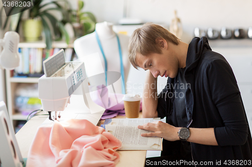 Image of fashion designer reading book at studio