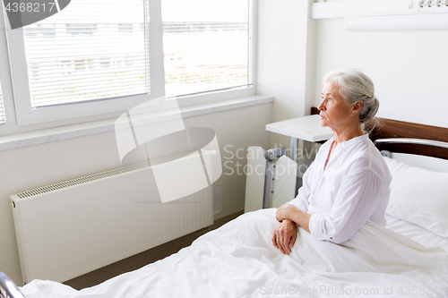 Image of sad senior woman sitting on bed at hospital ward