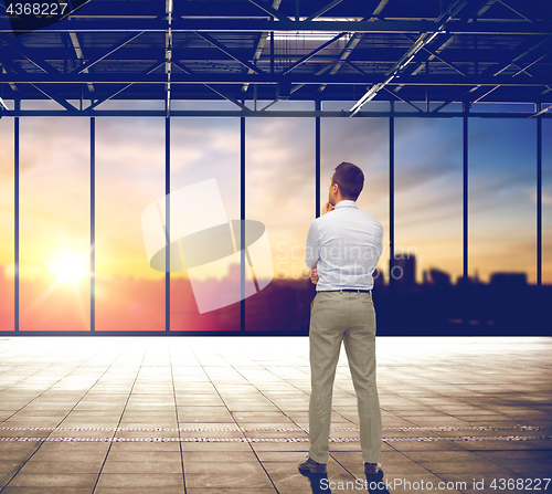 Image of businessman thinking over office and city view