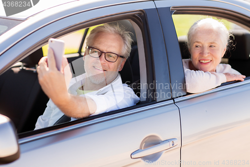 Image of senior couple in car taking smartphone selfie