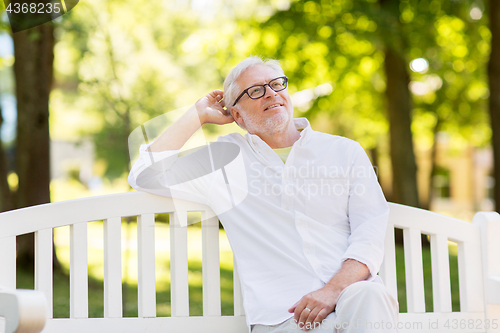 Image of happy senior man in glasses sitting at summer park