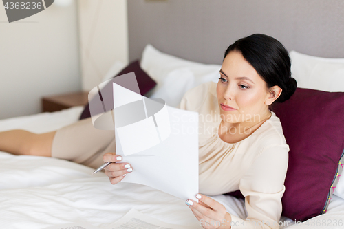 Image of businesswoman with papers working at hotel room