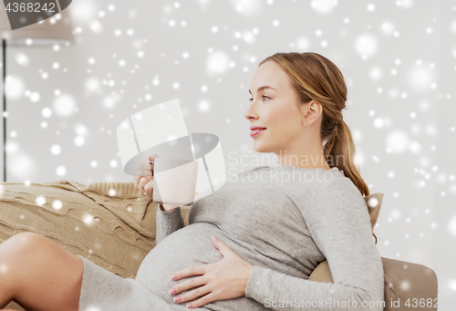 Image of happy pregnant woman with cup drinking tea at home