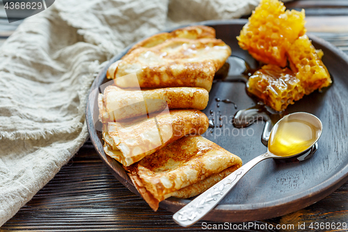 Image of Crepes with honey on a wooden plate.