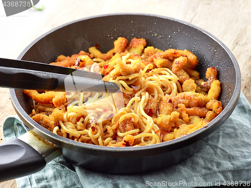 Image of Asian noodles with fried meat on cooking pan