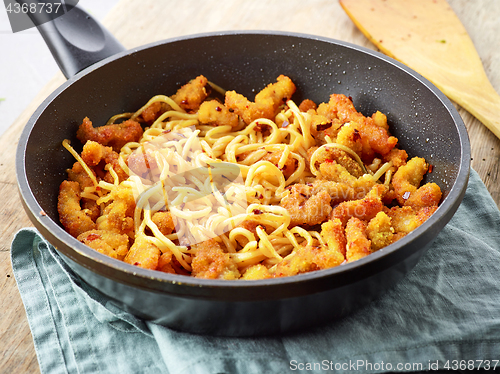 Image of Asian noodles with fried meat on cooking pan