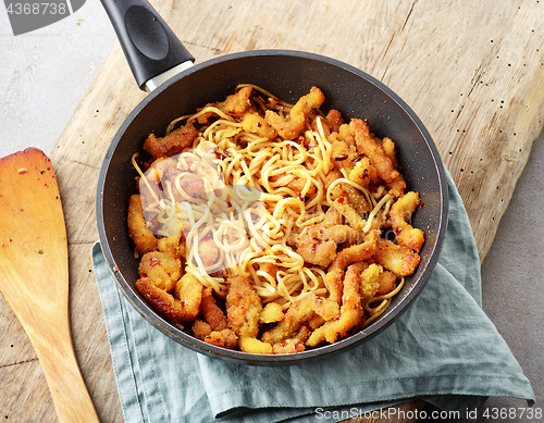 Image of Asian noodles with fried meat on cooking pan