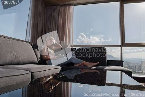 Image of young woman on sofa at home surfing web