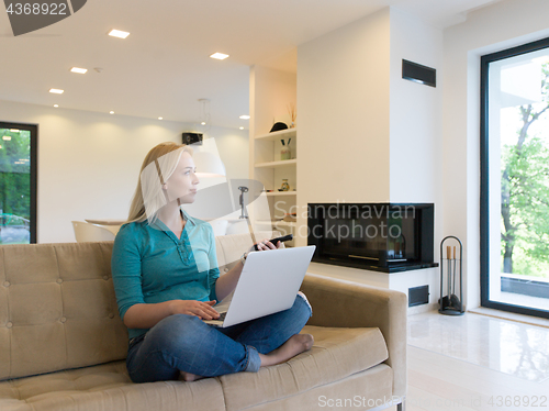 Image of Young woman using laptop at home