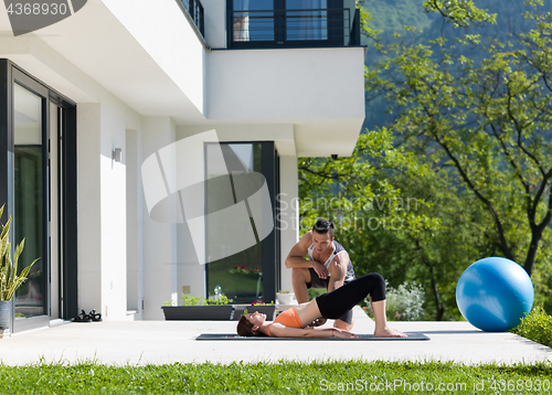 Image of woman with personal trainer doing morning yoga exercises