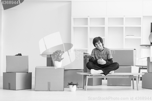 Image of boy sitting on the table with cardboard boxes around him