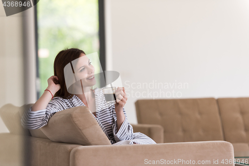 Image of young woman in a bathrobe enjoying morning coffee