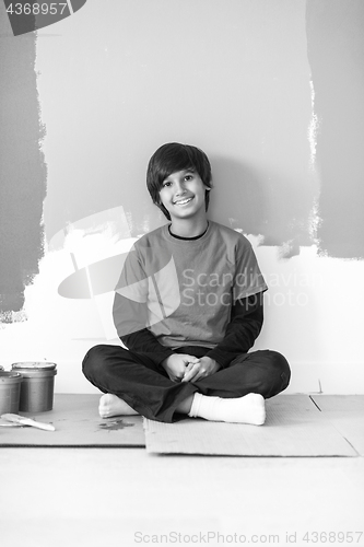 Image of young boy painter resting after painting the wall