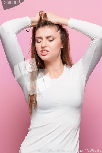 Image of Portrait of beautiful young brunette with bare shoulders touching her temples feeling stress