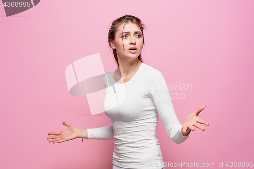 Image of The serious frustrated young beautiful business woman on pink background