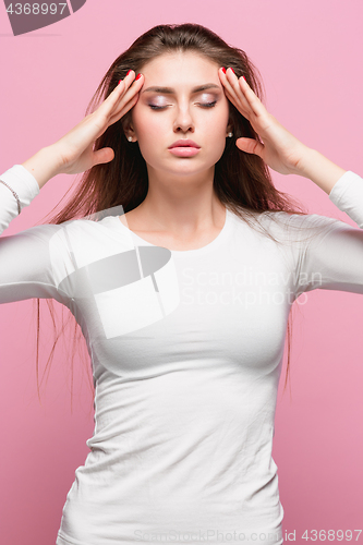 Image of Portrait of beautiful young brunette with bare shoulders touching her temples feeling stress