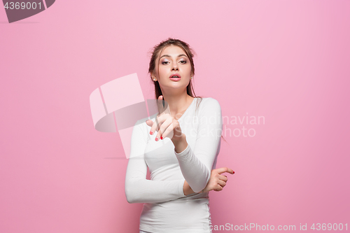 Image of The serious frustrated young beautiful business woman on pink background