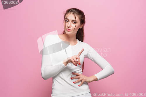 Image of The serious frustrated young beautiful business woman on pink background