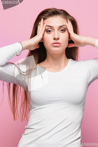 Image of Portrait of beautiful young brunette with bare shoulders touching her temples feeling stress