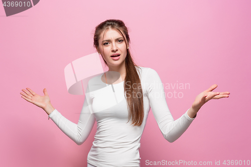 Image of The serious frustrated young beautiful business woman on pink background