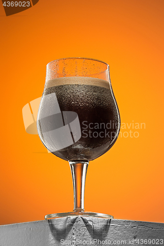 Image of glass of cold frothy dark beer on an old wooden table