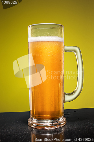 Image of glass of cold frothy lager beer on an old wooden table