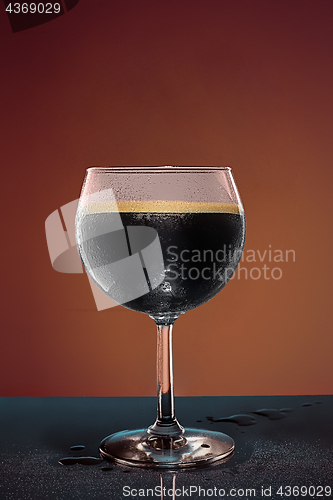 Image of glass of cold frothy dark beer on an old wooden table