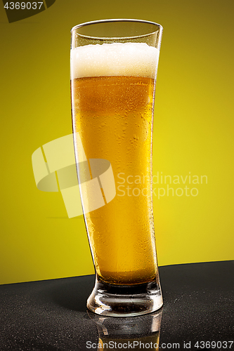 Image of glass of cold frothy lager beer on an old wooden table