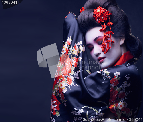 Image of young pretty geisha in kimono with sakura and decoration