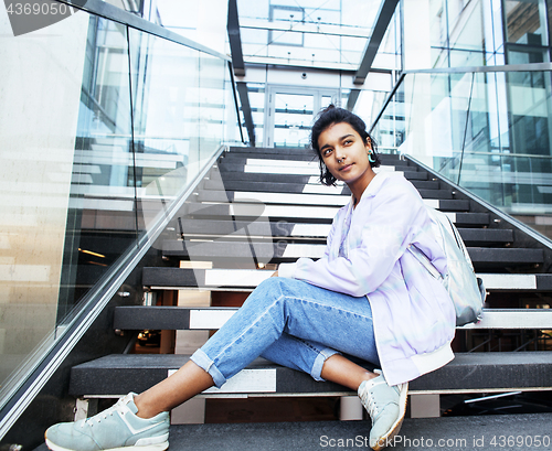 Image of young cute indian girl at university building sitting on stairs 