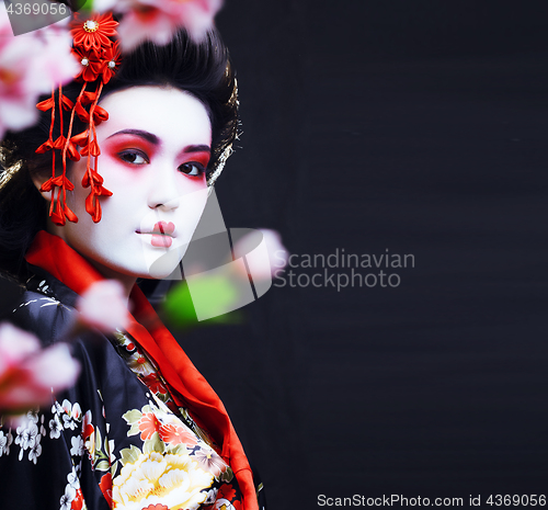 Image of young pretty geisha in kimono with sakura and decoration