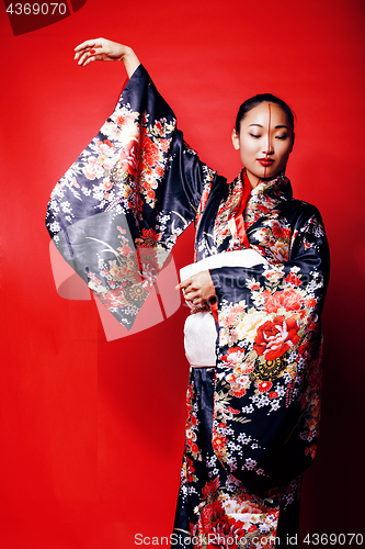 Image of young pretty geisha on red background posing in kimono, oriental people concept close up