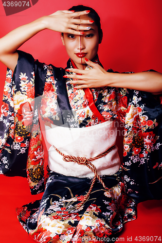 Image of young pretty geisha on red background posing in kimono, oriental people concept close up