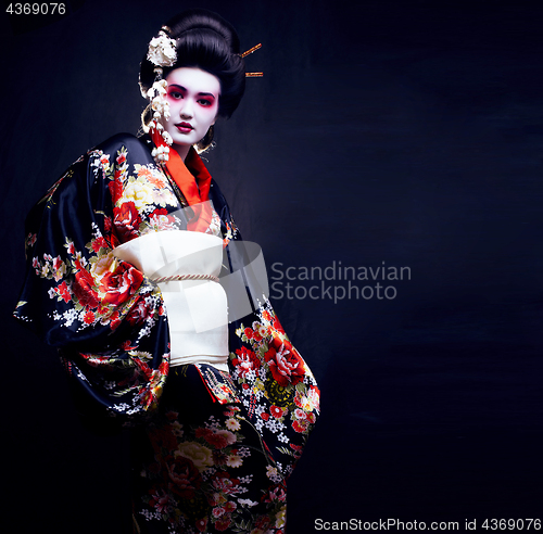 Image of young pretty geisha in kimono with sakura and decoration