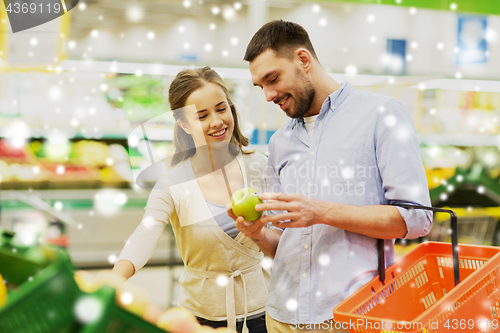 Image of happy couple buying apples at grocery store