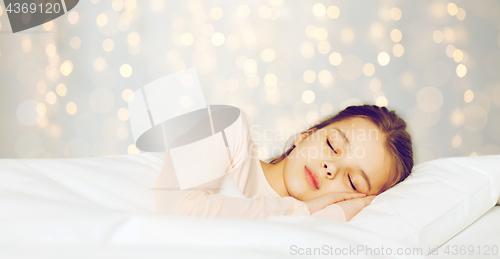 Image of girl sleeping in bed over holidays lights