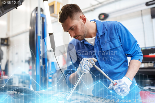 Image of mechanic man with wrench repairing car at workshop