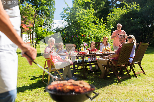 Image of man cooking meat on barbecue grill at summer party