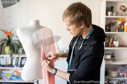 Image of fashion designer with dummy making dress at studio